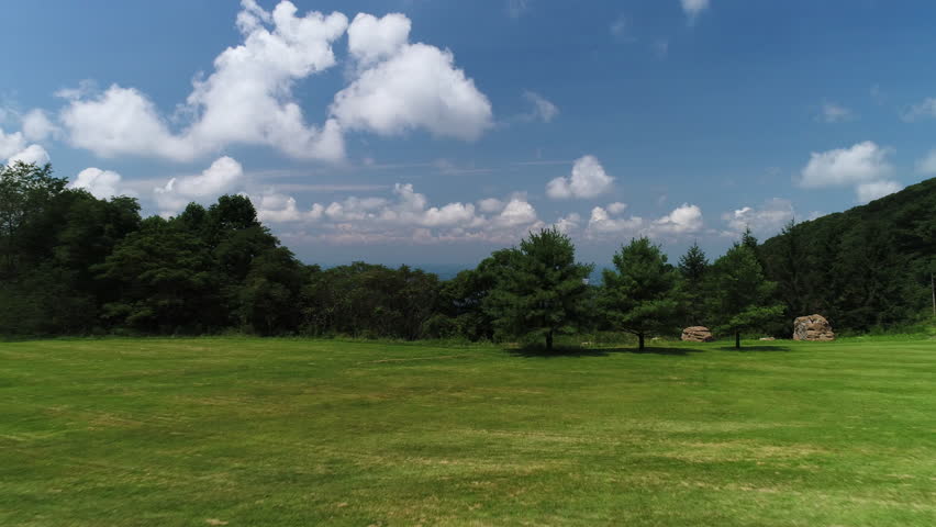 A rising aerial summer daytime view of the Pennsylvania landscape revealing the town of Unionville in the distant valley. Traffic on PA RT-40 National Pike in the foreground.  	