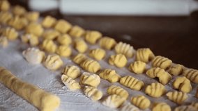 Video clip of woman cutting pasta for gnocchi on a wooden board.