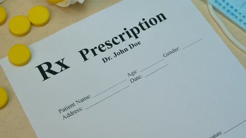 Healthcare professional doctor writing RX paper prescription for tablet pills or drugs