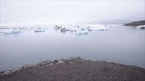 Slow motion- Girl walking to glacier lagoon in Iceland discovering the beauty if nature, icebergs floating on lake. Tourist female adventuring in Northern Europe - 