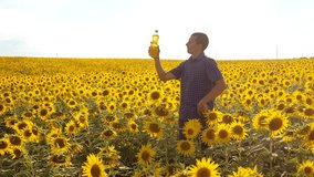 man farmer exploring the field lifestyle with sunflowers. slow motion video. Man lifestyle farmer hand hold bottle of sunflower oil the field at sunset. man farmer agriculture plastic bottle oil