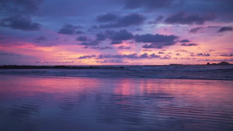 Out of focus background plate of remarkable purple and blue sunset on the beach in Costa Rica for compositing or keying. Blurred or defocused shot of ocean sun set for green screen composite. 4k