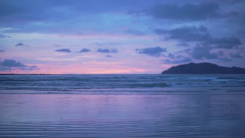 Out of focus background plate of pretty purple and blue sunset on the beach in Costa Rica for compositing or keying. Blurred or defocused shot of ocean sun set for green screen composite. 4k