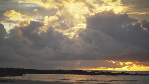 Background plate of beautiful Costa Rica sunset over the beach for compositing or keying. Orange sun setting with view of the ocean and white fluffy clouds. Out of focus shot for green screen. 4k