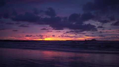 Out of focus background plate of dark purple and orange sunset on the beach in Costa Rica for compositing or keying. Blurred or defocused shot of ocean sun set for green screen composite. 4k