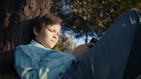 teenager playing video games on his smartphone outdoors. 4k footage