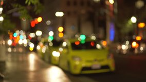 Background plate of out of focus taxi cab line parked on city street downtown at night. Blurry Video backdrop of urban area with bokeh lights for green screen compositing. 4k