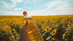 farmer holding a plastic bottle of sunflower oil in his lifestyle hand field sunlight. slow motion video. 