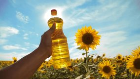 farmer holding a plastic bottle of sunflower oil in his hand field sunlight. slow motion video. 