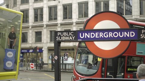 LONDON - APRIL 30, 2018: buses passing busy street, Underground subway station sign with people exiting in LDN, England, UK. The Underground serves 270 stations.