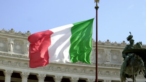 Italian flag waving against the equestrian statue representing the Italian King Vittorio Emanuele II. Altar of the Fatherland from Piazza Venezia, Rome, Italy