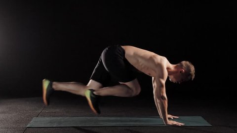 Strong sportsman working out on mat doing abs