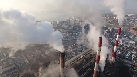 Aerial Close Top Smoke steam thermal power plant pipes large electric power industrial factory urban. Thick cloud pollution extinction burning Vladivostok Russia Winter snow sun Drone