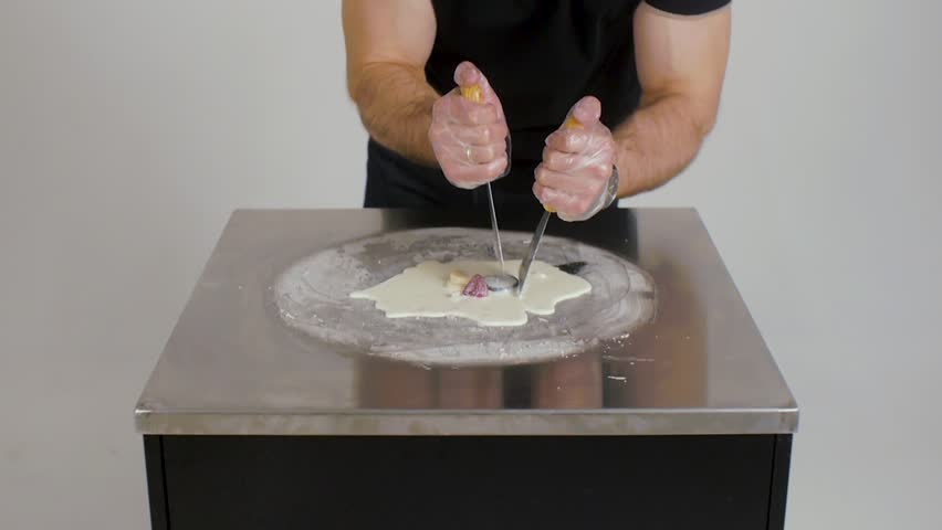 Cooking natural fruit ice cream in Thai style. Making ice cream rolls on cold plate. Thai style stir-fried rolled ice cream