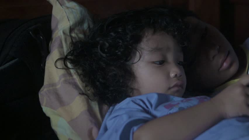 Two cute children playing smartphone on the bed after wake up in the morning