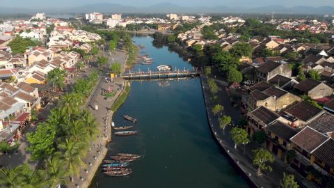 Aerial drone cinematic footage of the town of Hoian in Vietnam, South East Asia, with fishing boats and reflective water in the canal. Hoian is a very popular tourism destination in Vietnam .