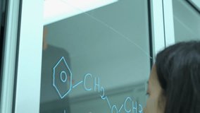 Scientist writing molecular formula on glass wall in modern laboratory or medical center. Concept of science, testing development and lab industry.