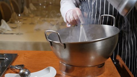 Cooking in restaurant. Cooker at work. Proffessional chef in gloves cooks dessert with dry ice. Chef pours water into bowl with dry ice. Slow motion.