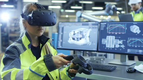 Factory: Female Industrial Engineer Wearing Virtual Reality Headset and Holding Controllers, She Uses VR technology for Industrial Design, Development in CAD Software. 