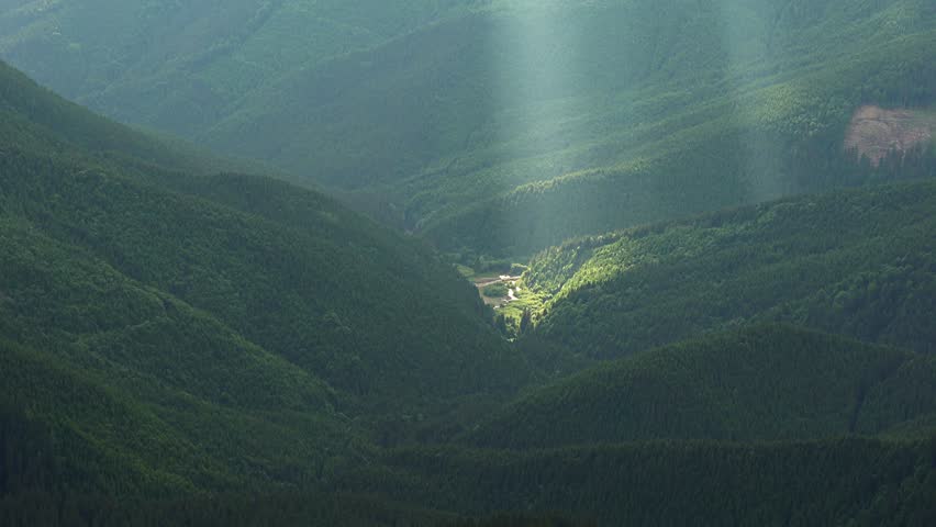 Mountain valley illuminated by the sun, rays light of sunset above the hills, mountains in the rays of the setting sun,  sun lit by the forest on the slopes of the Carpathian Mountains