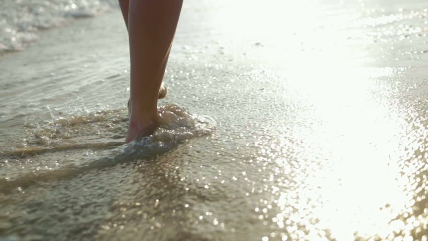 Feet of a young girl walking on the beach at sunset. Close up | Shutterstock HD Video #1015054351