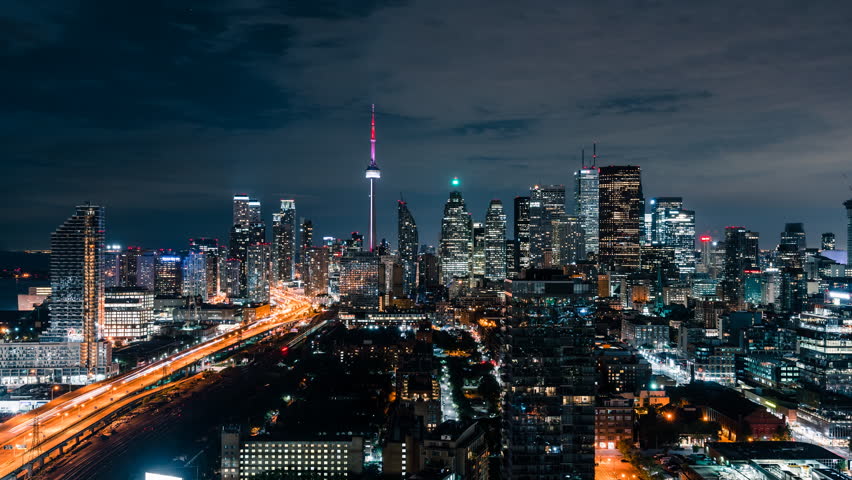 Huge epic wide city skyline views at night of the Toronto Canada downtown core. Office buildings, condominiums and urban modern architecture layer the skyline. Gardiner Expressway car traffic. Royalty-Free Stock Footage #1015058800