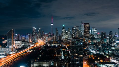 Huge epic wide city skyline views at night of the Toronto Canada downtown core. Office buildings, condominiums and urban modern architecture layer the skyline. Gardiner Expressway car traffic.