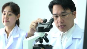 Male and Female scientists looking through microscope and memo writing observe in modern laboratory or medical center. Concept of science, testing development and lab industry.
