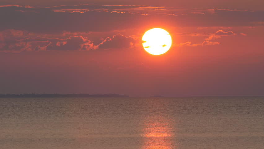 Dramatic sunset with fiery red sun on Lake Nipissing, Ontario, Canada. Manitou Islands Provincial Park in the distance.