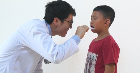 Doctor Man Examine Mouth Of Small Boy
