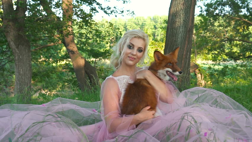 Beautiful young woman with cute fox at forest.