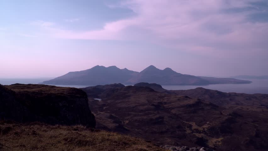 Wide-shot from the top of Eigg looking over to the sunset silhouette of the Isle of Rum.