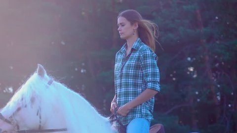 Young woman riding horse during a summer sunset. Slow Motion