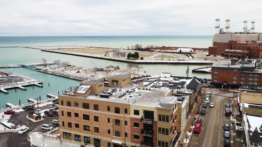 Low altitude, cinematic aerial footage of a town by the lake during winter/fall. Port Washington, WI.