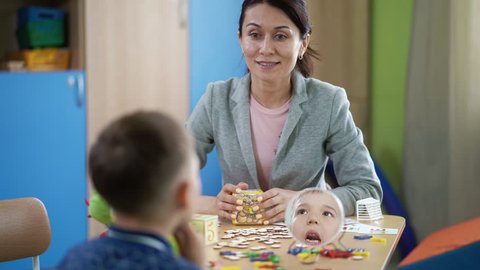 The woman speech therapist teaches the boy on therapy session