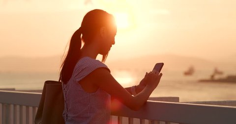 Woman use of mobile phone under sunset วิดีโอสต็อก