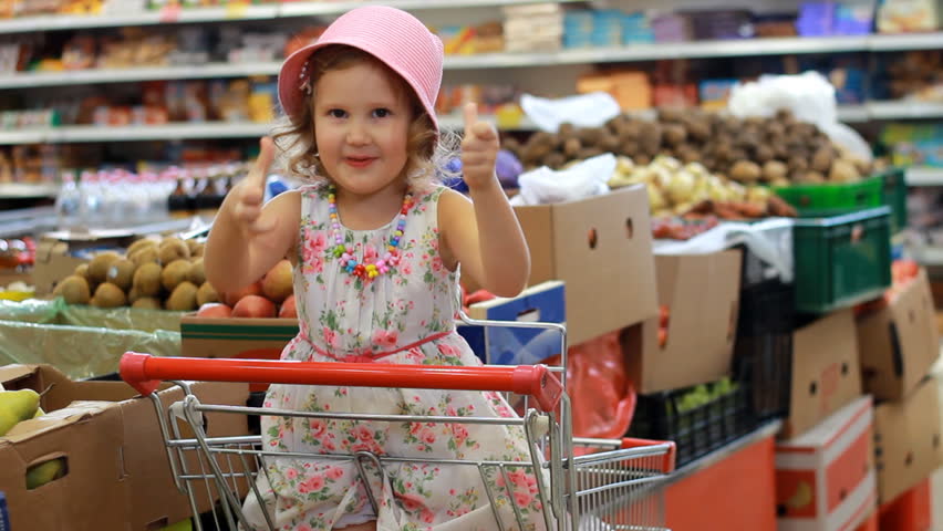 Girl in the store chooses fruit. Grocery supermarket and shopping trolley