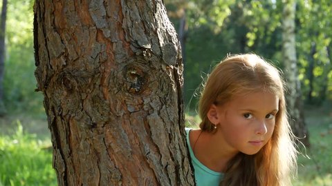 The girl looks out of the tree, looks around and hides. Sign to keep silent.