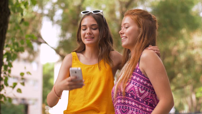 friendship, leisure and technology concept - smiling teenage girls taking selfie by smartphone in summer park
