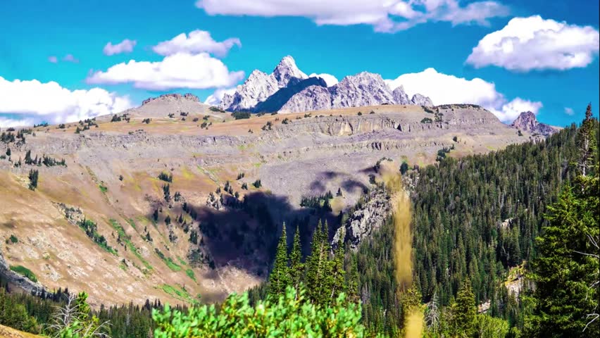 Time lapse of Grand Teton Peak during the daytime. Camera is in a fixed position above the canyon as it watches the clouds and fauna flow in the wind. 