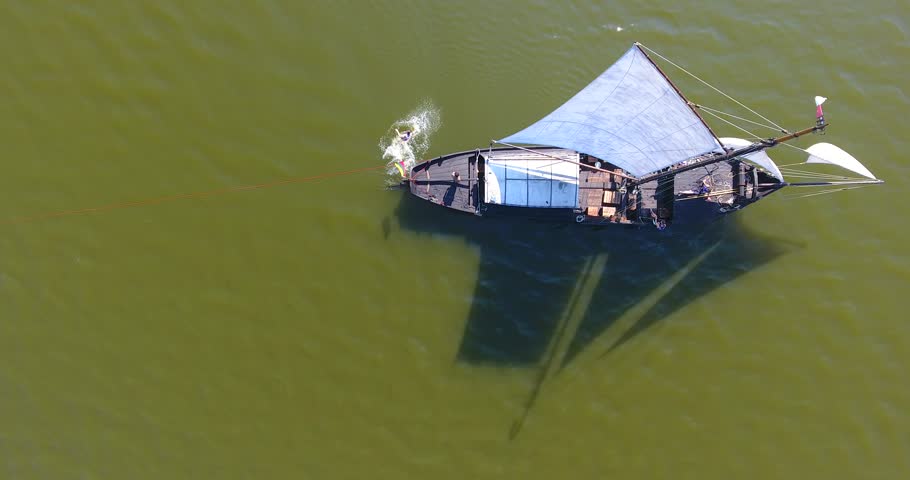 Sailing through the lagoon - a historical, sailing boat. Aerial view is approaching from the shore, around it, near and from the top. Beautiful sunny day. The smooth surface of the lagoon water - 013