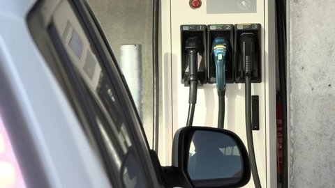 Nissan Leaf EV stopping at professional charging station with 3 plugs