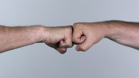 Two men fist bumping against white screen.