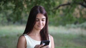 young beautiful girl using smartphone in the forest