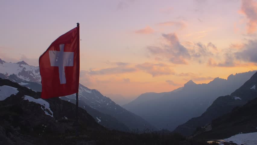 Swiss Flag. Alps mountains landscape during sunset. Sustenpass, Switzerland - Landscapes of the mountains and the nature of the Susten region. Royalty-Free Stock Footage #1015110520