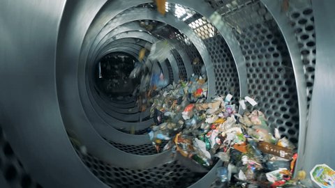 Trash is revolving inside an industrial recycling machine. Waste recycling equipment.