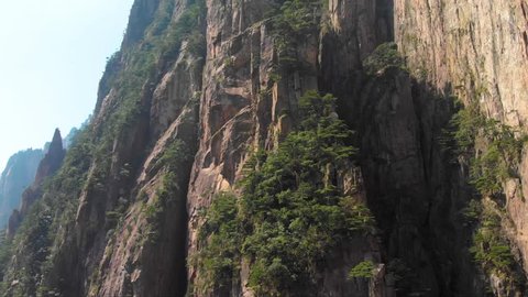 Drone aerial shot rising up over Huangshan mountain in China. Flying epic nature landscape shot of Yellow mountain. Close up of rock formations in famous tourist scenic spot.
