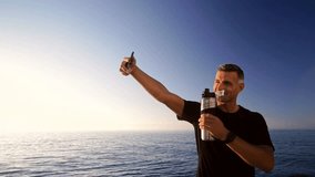 Joyful sports man making selfie on smartphone with bottle on sunrise at the beach