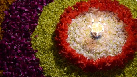 Footage of Flower rangoli for Diwali or Pongal or any hindu festival  using marigold or zendu flowers and red rose petals with glowing diya or Samai, selective focus