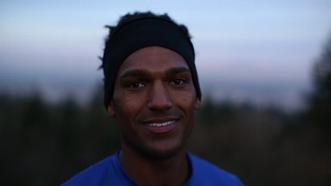Handheld close-up portrait of happy athlete against sky at dusk